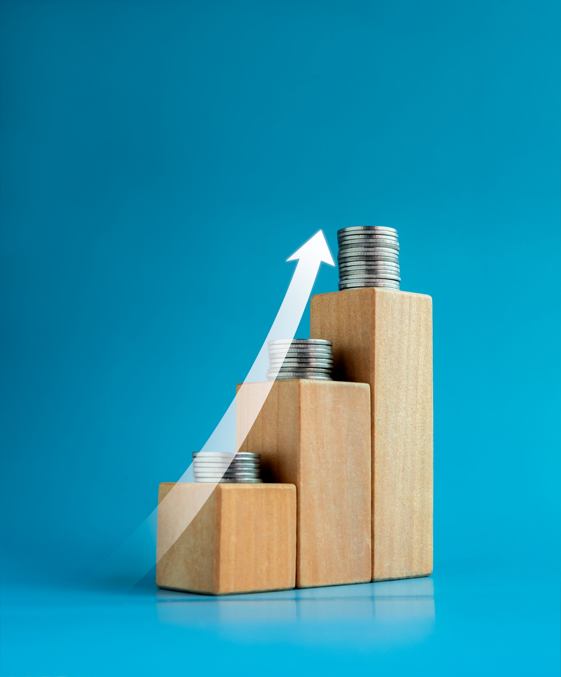 Shining rise up arrow on wooden cube blocks with coin stacked, b Shining rise up arrow on wooden cube blocks with coin stacked, bar graph chart steps on blue background, investment, profit, benefit, income, banking, business growth, economic improvement concepts.