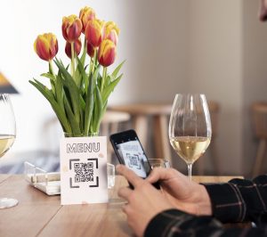 Someone scanning a QR code at a restaurant whilst drinking wine.